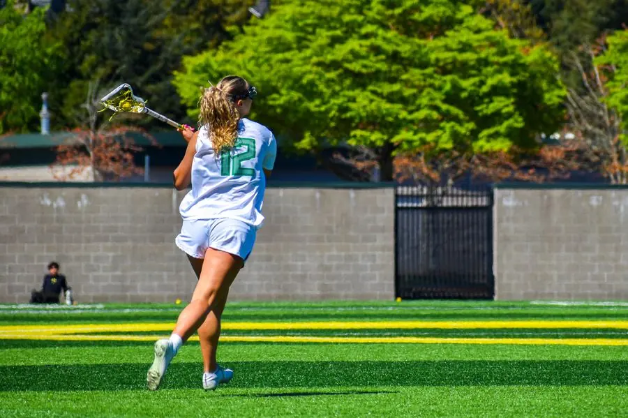 Oregon lacrosse player cradling the ball downfield
