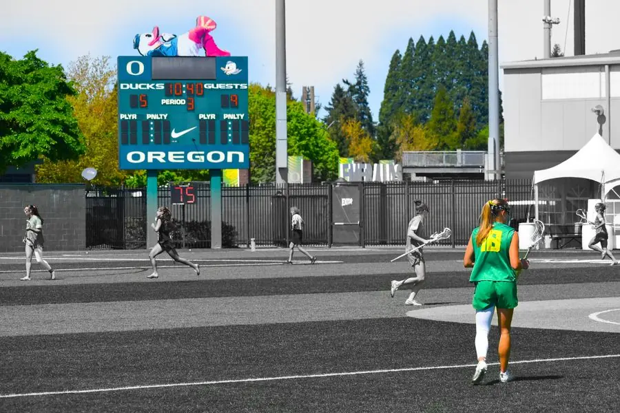 Oregon lacrosse player running past the scoreboard