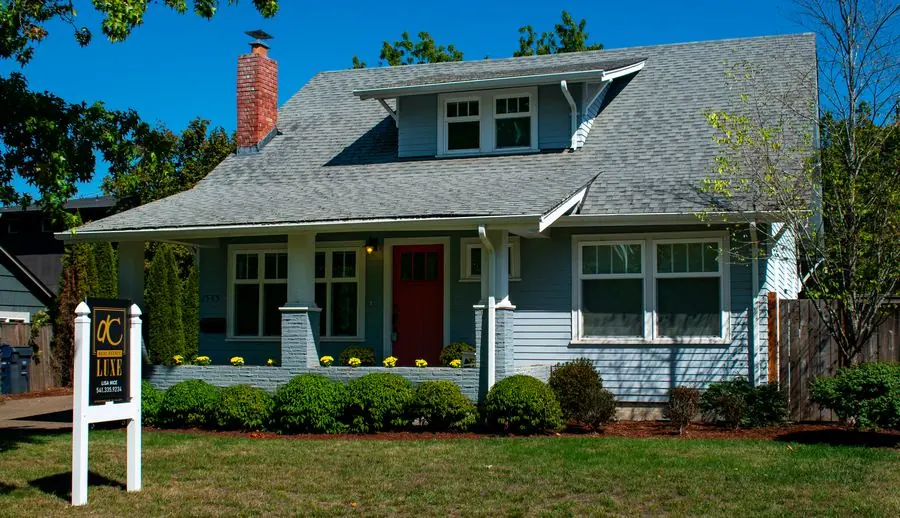 Craftsman-style home with a red front door and a Real Estate Luxe for-sale sign