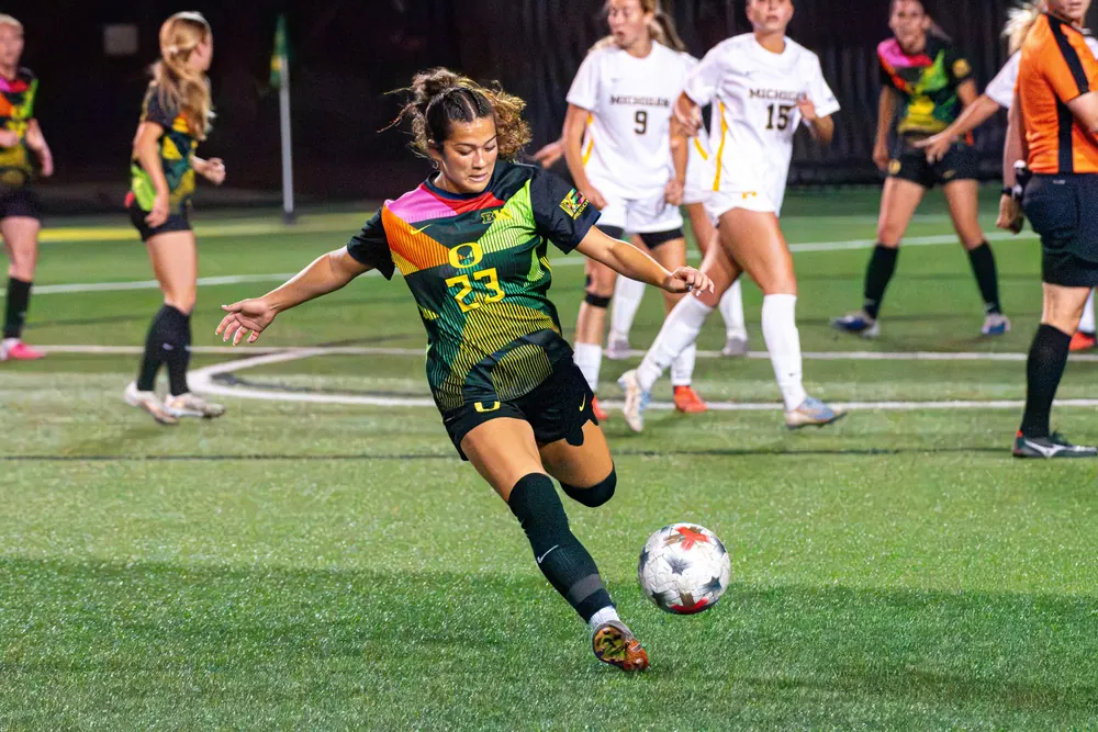 Oregon women's soccer player No. 23 winding up to strike the ball against Michigan
