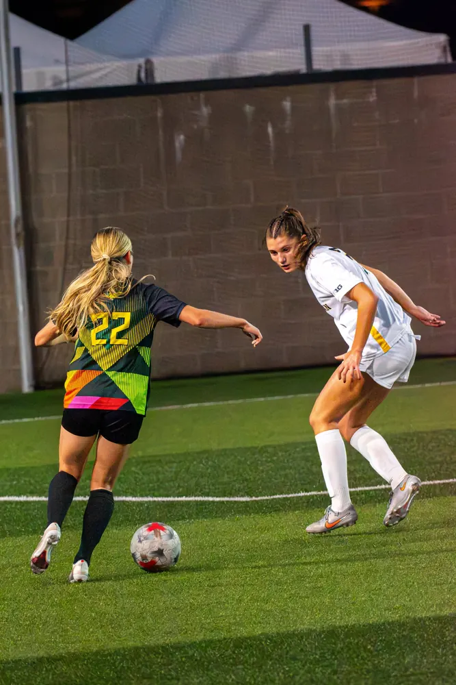 Oregon women's soccer player No. 22 taking on a Michigan defender down the sideline