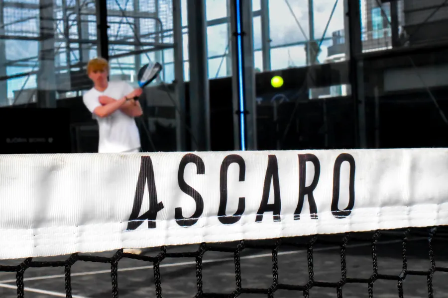 Padel player lining up a backhand behind the net