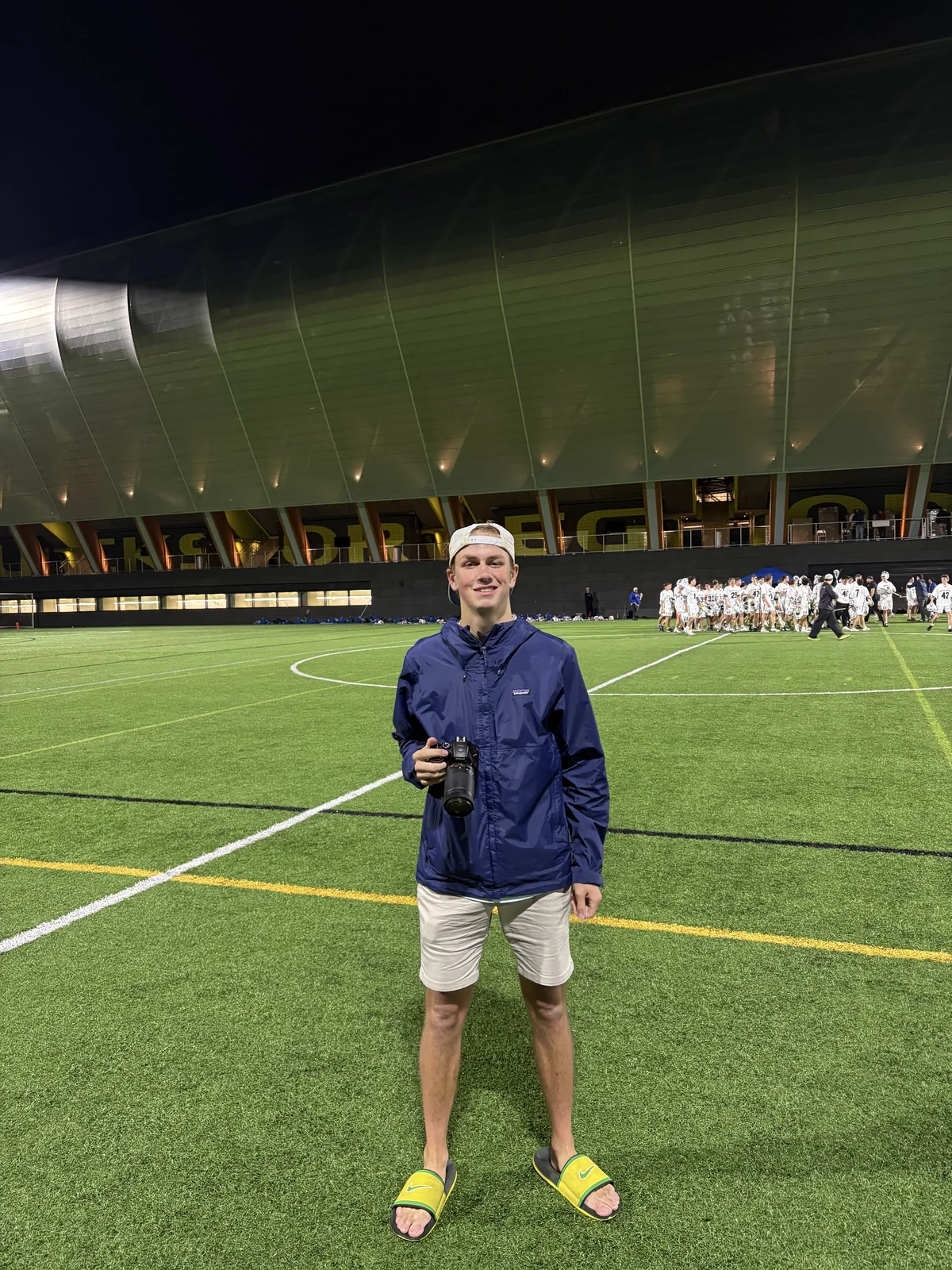 Photographer holding his camera on the field after a night lacrosse game